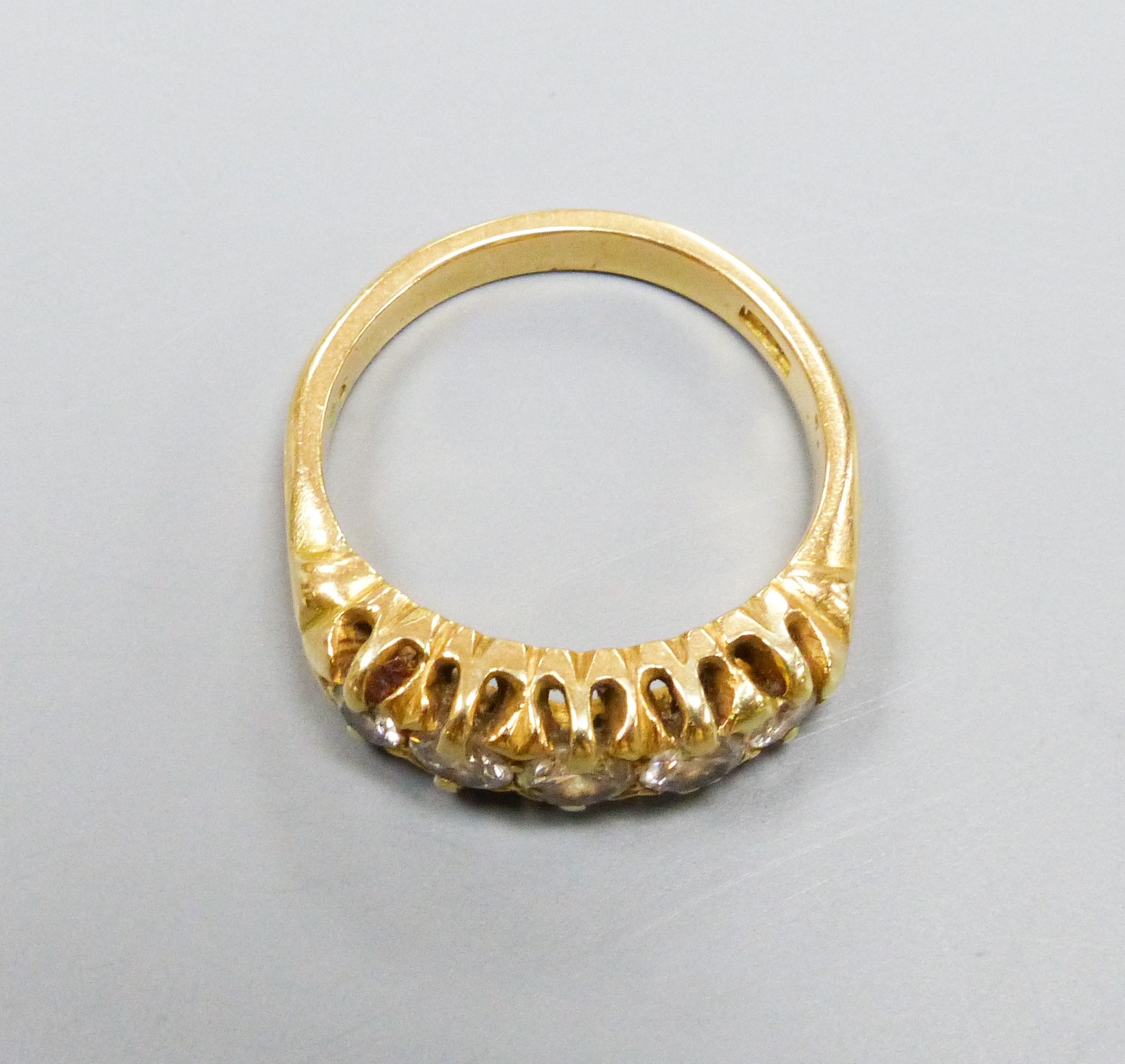 A five-stone diamond ring, 18ct yellow gold setting, claw-set with carved shoulders, size K, gross 5.5 grams.